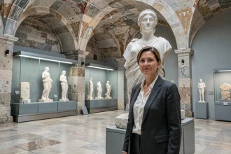 Conservatrice de musée debout devant une réplique en marbre de la statue d'Athéna Parthénos dans un musée archéologique